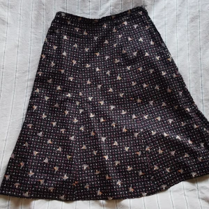 Vintage-kjol - Fodrad kjol i polyester med fint mönster. A-linje. Stängs med dold dragkedja i sidan. Bra skick. Längd:70 cm Omkrets linning: 74 cm. Omkrets nedtill: 176 cm. 