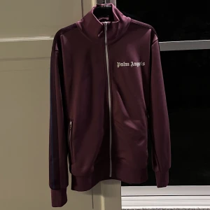 Palm Angels Track Top - Palm Angels tracktop i ovanlig lila färg, stripes i lila och blått istället för den klassiska vita stripen. Sprillans ny med tags, nypris 5000. Storlek S och är true to size, vid frågor och funderingar är det bara att höra av sig! :) Tar emot bud!