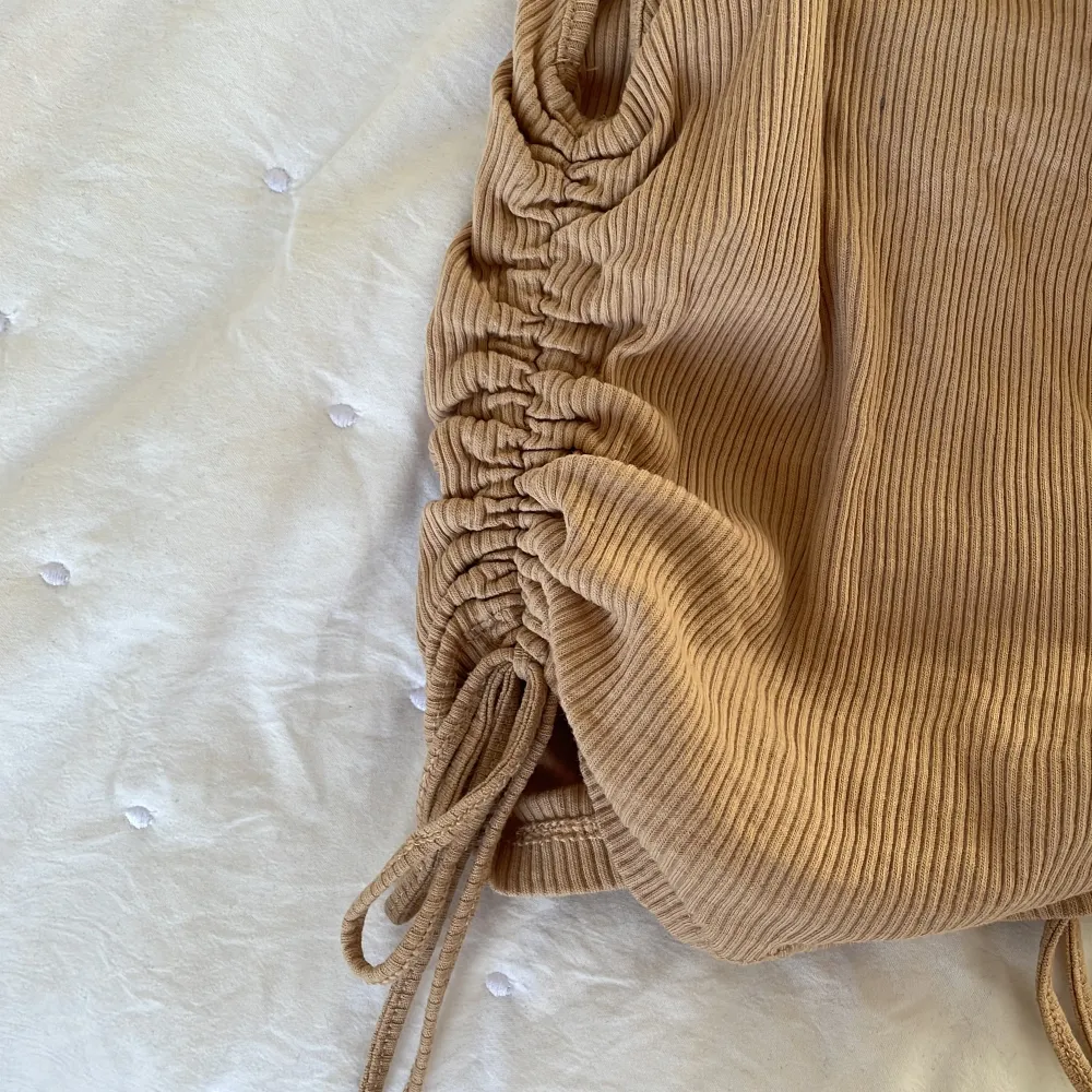 Ett beige linne från H&M, divided. Har inte kommit till användning. Små knyte på sidan där man kan spänna åt hur mycket man vill ha den cropad!!😍(ser litet ut men är jätte ”töjbar”). Toppar.