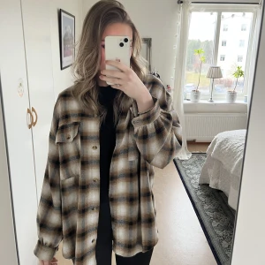 Rutig skjorta - Brun/ svart/ vit rutig skjorta. Lite längre baktill. 