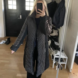 Junge lång jacka i storlek 38 - Så snygg Junge jacka i storlek 38. Den är i väldigt bra skick! Nypris ligger runt 3500kr. En jacka av väldigt bra kvalitet som är så skön och värmande! Färgen är olika men den är svart och lite gråbrun. Grå/brun/mörkbeige