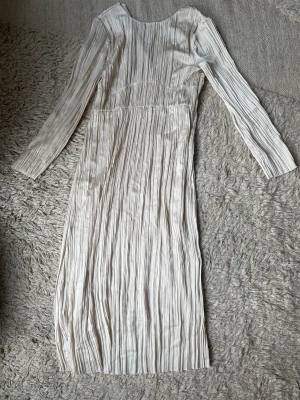 Långklänning  - Strl 40 Créme vit Lång krinklad klänning Använd 1 gång, inga tecken på användning  Lite längre än midi och lite kortare än Maxi på mig som är 170. Man ser en bit upp på anklarna, en väldigt fin längd enligt mig. Blir inte tantigt på samma sätt som vissa m