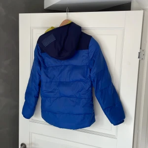 Kjus jacka  - Kjus jacka perfekt för barnen om man ska åka på skidsemester en liten skada som man kan se på kort 3 och små fläckar här och där men funkar toppen Skick 5/10
