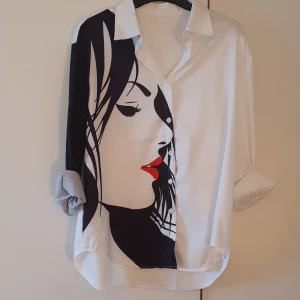 Skjorta vit/svart Medium  - Superhäftig skjorta i vitt/svart med ett kvinnoansikte. Helt ny/oanvänt endast provad. Ani gen längre bak än fram. Står xl men passar medium eller small för oversize. Pris 180kr 