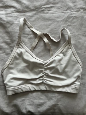 Gymshark sport-bh  - Ruched sports bra från Gymshark! Vit men blivit något mörkare i tvätten, inget som stör dock men därav priset. Fint använt skick 