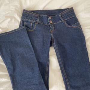 Säljer ett par mörkblå lågmidjade bootcut jeans i storlek 38 med två knappar, det är bara att fråga för mer bilder eller annat!💗midjemått 38, innerbenslängden 78💞