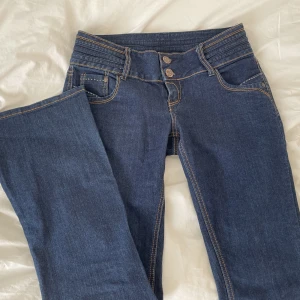 Lågmidjade jeans💗 - Säljer ett par mörkblå lågmidjade bootcut jeans i storlek 38 med två knappar, det är bara att fråga för mer bilder eller annat!💗midjemått 38, innerbenslängden 78💞