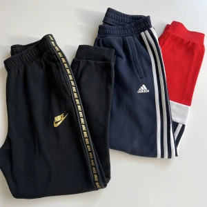 Nike och Adidas mjukisbyxsor  - Två par byxor, I nyskick. 70kr/styck, säljs även separat. Nike byxa: Svart med guld detaljer. Storlek 158. Mjukisbyxa.   Adidas byxa: flerfärgad (röd, vit och blå) med adidas detaljer. Storlek 150.