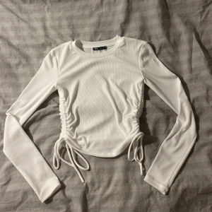 Vit långärmad topp  - Vit långärmad topp med knyte på sidorna från Zara. Endast använd en gång. Nyskick. 