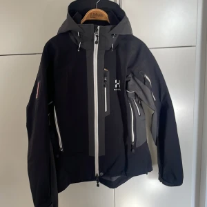 Jacka - En allvädersjacka som både står emot regn och blåst. I mycket gott skick. Många bra fack i och utanpå jackan