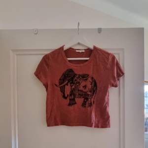 T-shirt med tryck av en elefant på. Väldigt lätt material. Jag passar personligen inte i röd säljer därför