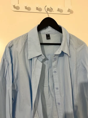 En ljusblå skjorta  - En skjorta som är i nyskick. Väldigt fint material. Köparen står för frakt!