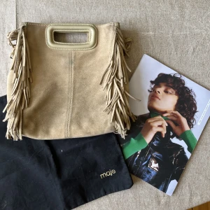 maje väska - beige maje väska! kommer med dustbag och en bok man fick med när jag köpte den. har inte kvar långa bandet men den kommer med kedjan. rätt smutsig (därav priset) men går säkert att tvätta med mockaborste🥰. 