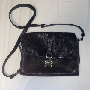 Tiger of Sweden väska - Superfin Tiger of Sweden handväska/axelremsväska! Finns lite slitage på axelremmen. Det saknas bl.a en gulddetalj på ena sidan (se bild) som behövs fixas och bandet är slitet överlag, därav billigt pris.