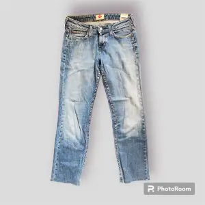 Ett par lågmidjade ljusa jeans i en rak modell. Slitningar finns! 