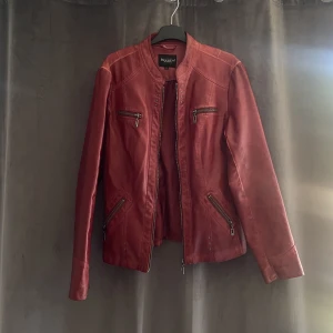 Röd skinnjacka  - En röd skinnjacka med detaljer! Är storlek 40 men passar bättre 36/38!