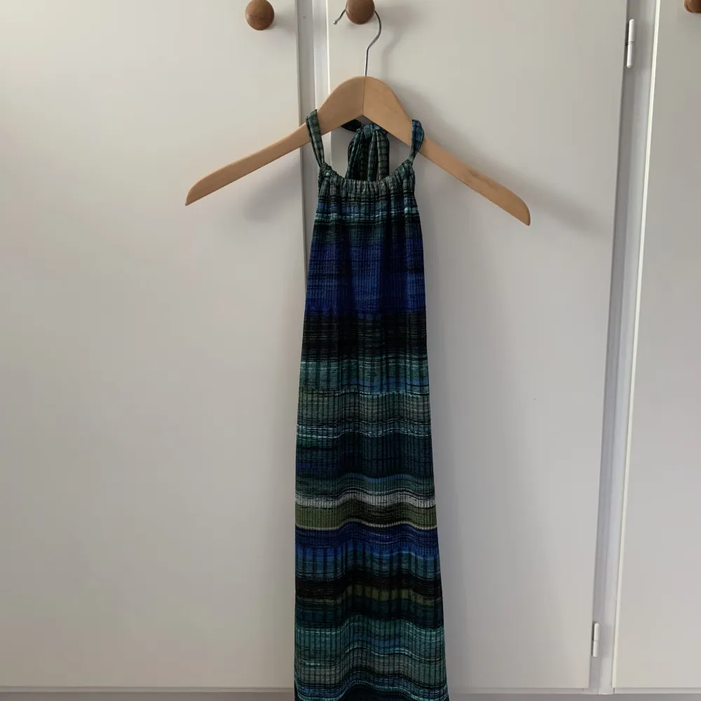 Så snygg halterneck klänning i grönt och blått med öppen rygg samt resår. Aldrig använd💚. Mekot.