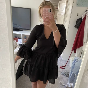Svart klänning med volanger - Säljer nu min absoluta favoritklänning, som tyvärr blivit för liten över bysten. Väldigt fint skick. Köpt på NA-KD. Skulle säga att den även passar en 36 då den sitter löst.