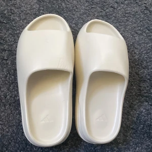 Yeezy Slides - Fick ett par yeezy slides i färgen ”bone” , som var alldeles för små. US 6 strl  Äkta men Har ingen box, drf kan sälja billigare. 