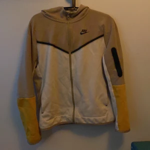 Nike tech tonåring  - En Nike tech tröja i vit och beige. Den är något använd men inget slitage eventuellt lite tecken på att den har tvättats