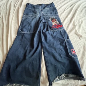 Baggy jeans med tryck - Tryck på högre fram-fickan och bakfick med extremt stora bakfickor. klippta lite på botten. Var 30/30 nu 28/30.
