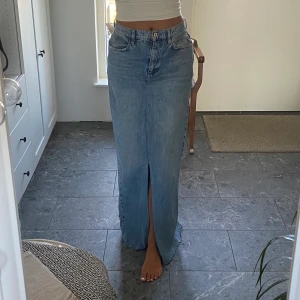 Lång jeans kjol  - Lång snygg jeanskjol i midwaist med slits både fram och bak. Storlek W28 jag är 173cm lång. Den är från märket Collusion.