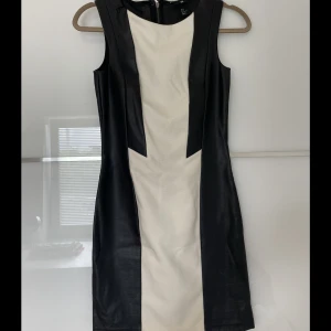 Svartvit klänning  - Klänning från H&M, strl 36, har rivits upp vid axeln på ena sidan.