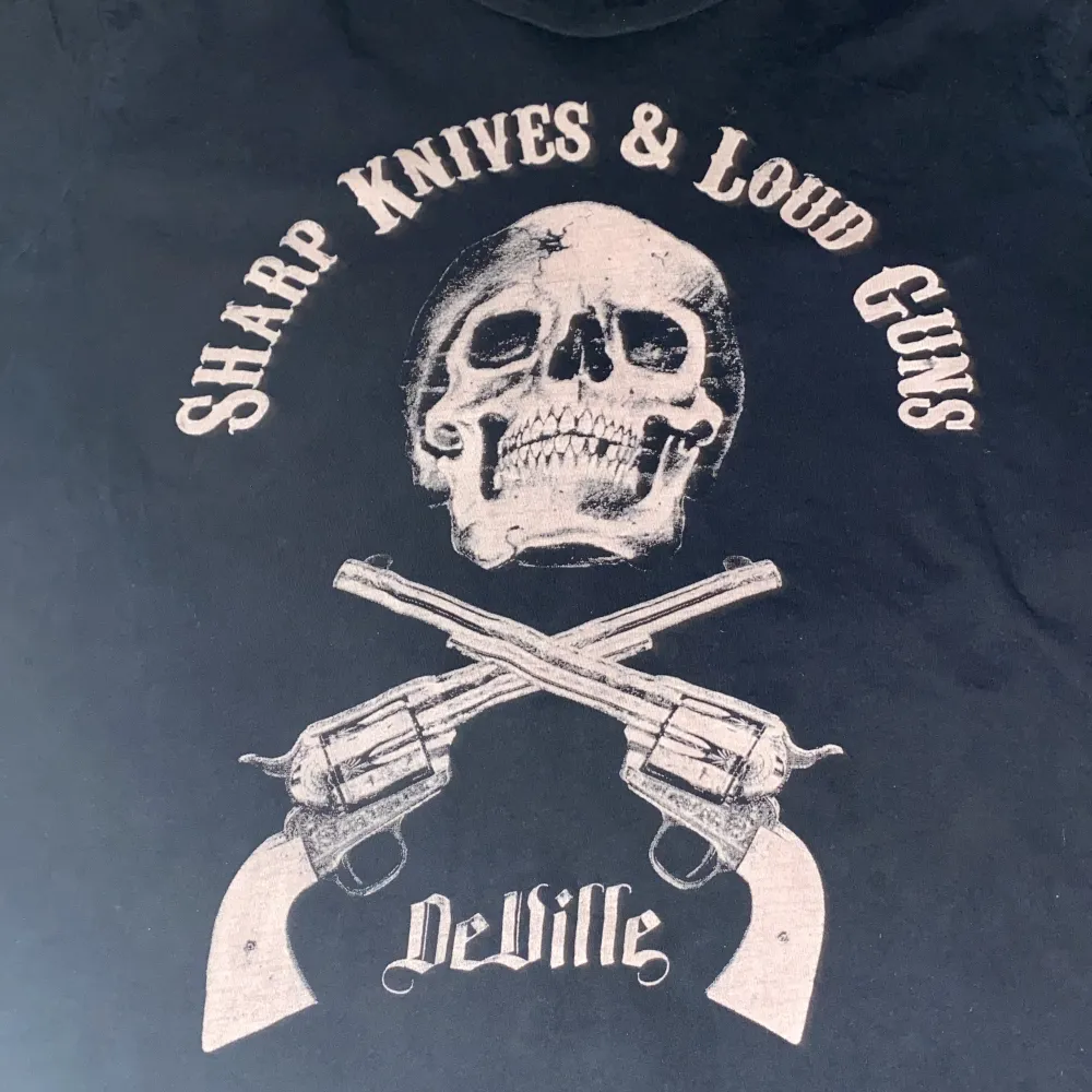 Deville t-shirt ”sharp knives & loud guns”. Vet inte vart ifrån den är, finns ingen lapp. Cool skalle och pistoler tryck.  Använd köp nu!. T-shirts.