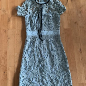 Spetsklänning  - Fin ljusblå spetsklänning med svart band runt halsen. Aldrig använd så passar som ny. Skriv privat för fler bilder.