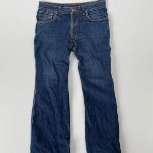 Förnya din garderob med ett par mörkblå Nudie jeans! Med sin djupa mörkblå färg ger det dig en elegant och mångsidi look som som är perfekta för alla tillfällen! Jeansen är väldigt stora i storleken och sitter som W32 L32