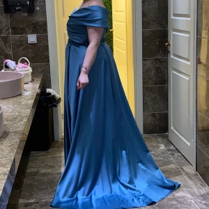 Festklänning med slits  - Strl 48. Kemtvättad och använd endast 1 kväll. Jättefin blå färg, väldigt elegant till bal eller bröllop. Priset kan självklart diskuteras. 