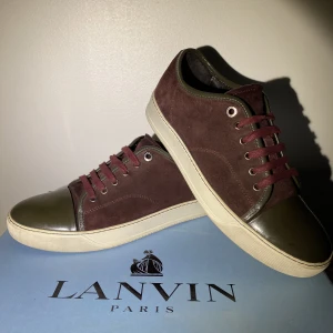 Lanvin Cap Toe Sneakers Ruby - Hej, säljer ett par väldigt snygga Lanvin Cap Toe Sneakers i Vinröd färg med grön toebag. Skorna är i väldigt bra skick både på mockan och toebag. Size 8=42/43. Unika och snygg colorway. Nypris 4000kr. Pris inte hugget i sten. Hör av dig vid frågor. 