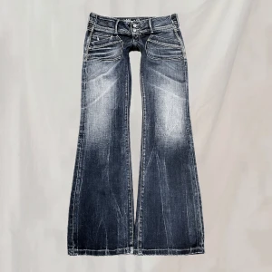 Lågmidjade jeans - Midja:83 Innerben:85 Lågmidjade jeans vintage från Hilfiger. Sitter bootcut/ganska rakt. Storlek w30, håller upp på bild. Blå färg med lite inslag av grönbrunt. Bra men vintage skick i form av nötningar (bilder ex.) samt nötta fotändar.🤍