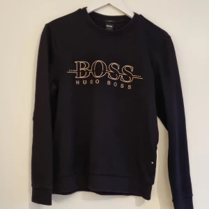 Hugo boss tröja - Svart med guldigt märke. Slim fit. Fint skick.