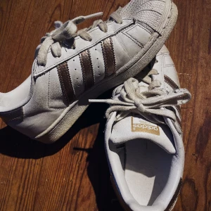 Adidas superstar sneakers  - Vita adidas sneakers med Roséguld detaljer. Storlek: 36 1/2  I fint skick, använt va 5-6 gånger.