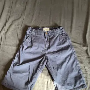 Dessa mörkblå shorts från Hampton Republic är oanvända, i storlek 164, 50 cm långa och 36 cm i midjan med resår. De är gjorda av Chino-material och har både fram- och bakfickor. Hör av er om ni har några frågor!