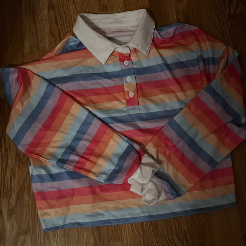 En långärmad tröja med knappar i massa olika färger.. Skjortor.