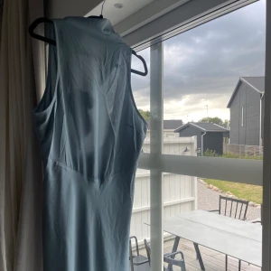 Blå långklänning  - Blå/turkos långklänning med öppen rygg och knytning runt halsen från NAKD. Helt oanvänd och prislappen kvar. Tyvärr för liten för mig. 