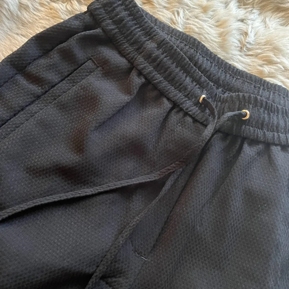 Ett par bekväma byxor som är kostymlikande. I strukturvävd kvalite med snören. I en svart färg. Storlek 34. Kan ej visa hur dom ser ut på då dom är små på mig. Använd 2-3 ggr endast.. Jeans & Byxor.