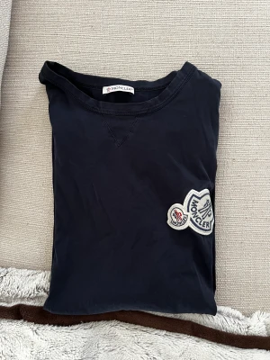 Moncler t-shirt, double logo  - En marinblå moncler t-shirt med dubbel-logga. Varan är 100% äkta och är köpt på NK. För mer bilder eller vidare information, tveka inte att kontakta! Ursprungpris: 2840kr. I fråga om frakt står konsumenten för detta. Betalningen sker via Swish.