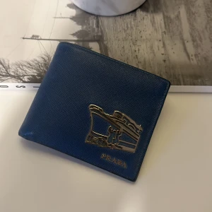 Prada plånbok - Prada plånbok i blått saffiano-läder, inte använd på länge. Köpt i Prada-butiken i Stockholm. Nypris runt 7 000kr.