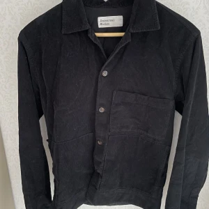 Universal works jacka  - En avslappnad jacka med 50-tals känsa tillverkad av 100% bomull. Den är försluten med 4 knappar och har två fickor som är fastsydda ner till och en elegant dubbel bröstficka