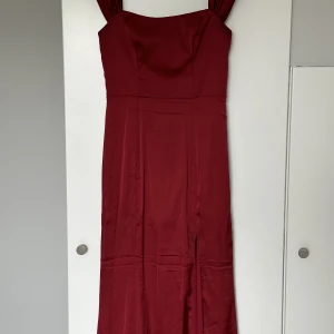 Röd Balklänning Nelly - Superfin mörkröd balklänning från Nelly i materialet satin, sitter som en smäck! Storlek 34, endast använd 1 gång så som ny. Axelbanden går att använda på 2 olika sätt, slits på sidan. Nypris 899kr Perfekt till Jul och Nyår!