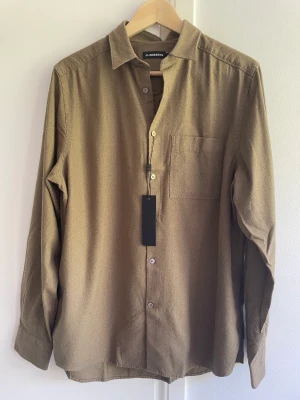J Lindeberg skjorta - Säljer denna J Lindeberg skjorta som är i helt nyskick, etiketten sitter till och med kvar! Den är i storlek M som var för litet för mig och är i färgen oliv grön som ser väldigt bra ut till sommaren! Nypris 1300kr