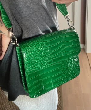 Axelremsväska  - Snygg axelremsväska i grön PU. Lätt och med avtagbara band och magnetknapp.  Inköpt i Berlin för några år sen, från märket Hvisk.