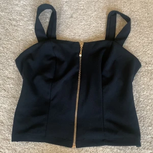 Söt topp med kedja  - En gullig topp med classy vibe. Den har en kedja fram och korsande band bak. Ingen tecken på användning.