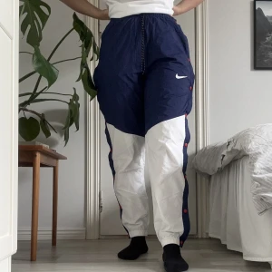 Trackpants - Ett par byxor med knappar längst sidorna av bena som man kan knäppa upp som man vill. De är i storlek S och i ett bra skick. 