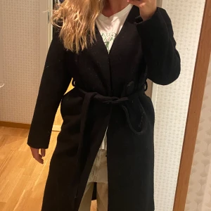 Svart kappa, filt material.  - Svart kappa, filt material. Knappar och skärp. Bra kvalitet. 