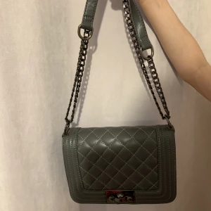 Väska - Mörkgrå väska. Banden går att justeras. 