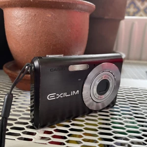 Digital kamera  - Casio exilim exz60. En asnajs bildkamera som även går att filma med. Bilderna blir 90s/00s. Medföljer inte minneskort, men har ett eget minnessystem så man ändå kan ta bilder. 9/10 skick